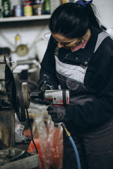 Wall Mural - Strong and worthy woman doing hard job in car and motorcycle repair shop.