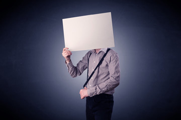 Young businessman hiding behind a blank piece of paper