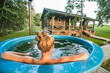 Woman enjoys outdoor hot tub in nature near wooden house