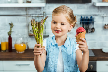 cute smiling child holding delicious ice cream cone and healthy asparagus