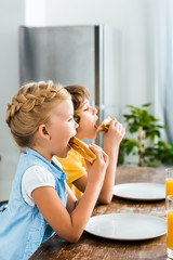 Wall Mural - side view of cute little children eating tasty sandwiches