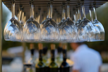 wine glasses stacked on black metal hanging bar glass racks in a bar