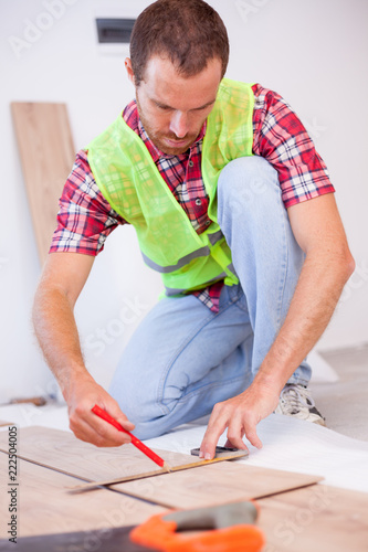 Young Man Wearing Reflective Safety Vest Installing Laminate