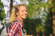 © Maridav - Hiking blonde woman healthy and active walking with backpack smiling happy in forest. Female hiker backpacker trekking in summer outdoors. Beautiful young adult girl living a happy lifestyle.