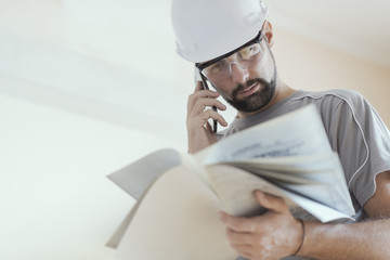 Wall Mural - Professional construction worker checking a project and calling