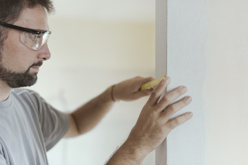 Wall Mural - Man measuring a wall using a folding ruler