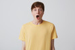 © timtimphoto - Closeup of astonished handsome young man with short haircut and opened mouth wears yellow t shirt shouting and looks shocked isolated over white background