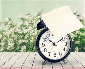 Retro alarm clock on flowers background