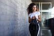 © javiindy - Young African woman with black curly hairstyle walking near business building