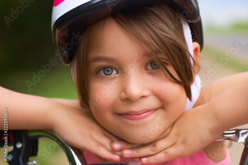 Fotografie, Obraz Close-up of a little girl's face on bike looking at camera and smiling