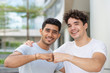© Mangostar - Portrait of happy multiethnic male friends making fist bump. Young Indian and Hispanic male students embracing, looking at camera and smiling outdoors. Male friendship concept
