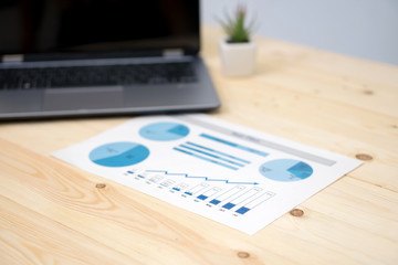  laptop and financial graph on white paper on working table