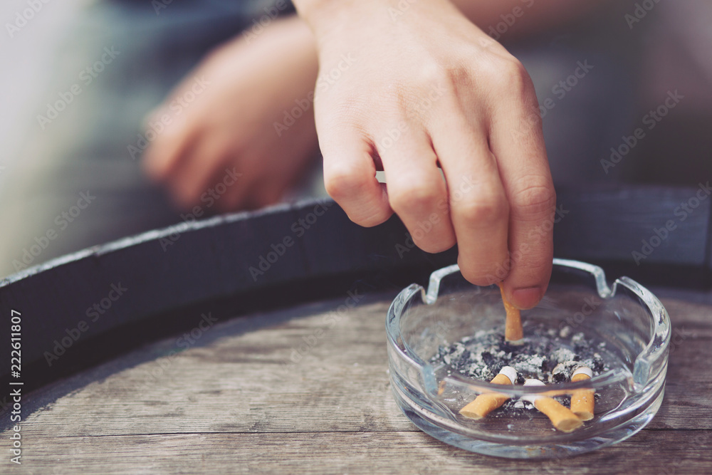 put out cigarettes people young man hand putting out a tobacco cigarettes ashtray.,cigarette  butt On a wooden bucket. Stock Photo