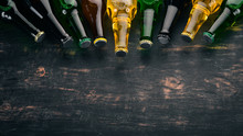 A Large Selection Of Beer Bottles. On A Black Wooden Table. Free Space For Text. Top View.