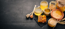A Set Of Honey And Bee Products. Honey In Honeycomb. On A Black Wooden Background. Free Space For Text. Top View.