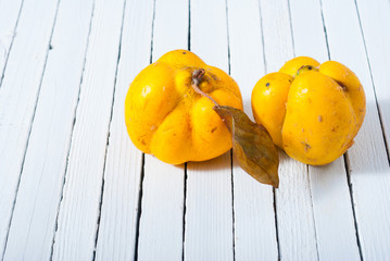 two quinces on white wooden background