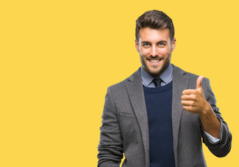 Young handsome business man over isolated background doing happy thumbs up gesture with hand. Approving expression looking at the camera with showing success.