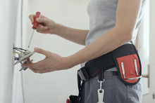 Female electrician fixing a socket at home