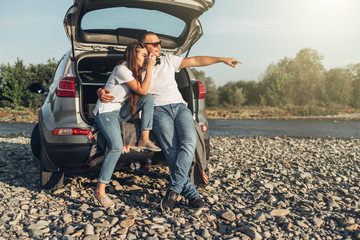 Wall Mural - Happy Couple on Roadtrip into the Sunset in SUV Car