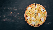 PIZZA QUATTRO FORMAGGI. Italian cuisine. On a wooden background. Free space for text. Top view.