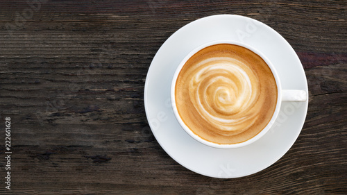 Photographie Hot coffee cappuccino latte spiral foam top view on dark wooden background