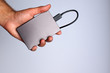 © droidfoto - A man's hand holds a portable hard drive on a gray background