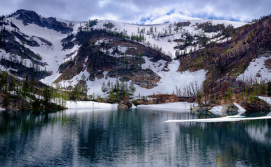  Snow covers the slopes of a ridge above a mountain lake