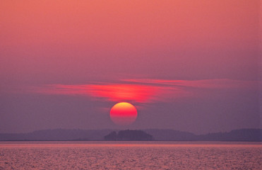Wall Mural - a hazy sunset with intense colors over lake in finland.