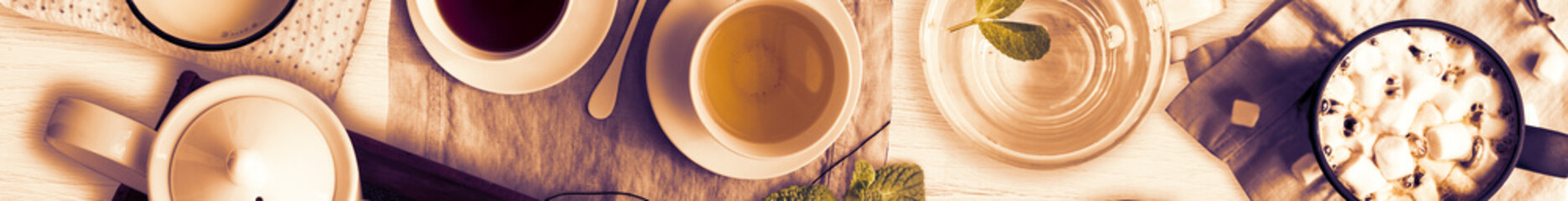 Set of different cold drinks and hot drinks - juices, coffee, tea, milk, mint water - cups and mugs served on white wooden table. Closeup. Top view. Wide. Full banner format.