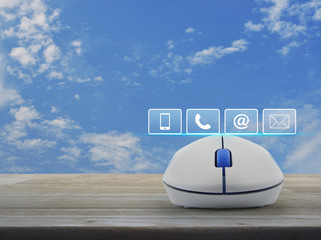 Telephone, mobile phone, address and email buttons with wireless computer mouse on wooden table over blue sky with white clouds, Business customer service and support concept