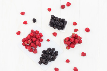 raspberries and blackberries white wooden background