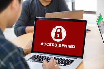 Protection security system concept. Man working on laptop with access denied text on screen.