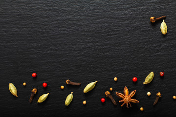 Wall Mural - Food presentation background organic various exotic spieces on black slate board with copy space