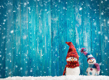 Little Knitted Snowmans On Soft Snow On Blue Background