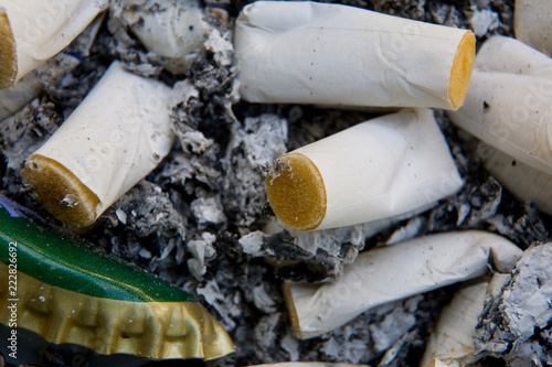 Fotografie, Obraz The lid of the bottle and cigarette butts lie in the tobacco ash.