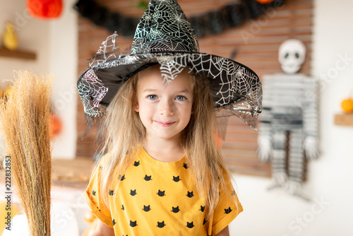 Cute Little Girl In Witch Costume With Hat Is Holding A