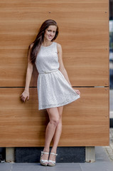 Wall Mural - Young girl in a white dress near a wooden wall
