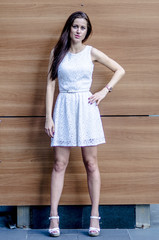 Wall Mural - Young girl in a white dress near a wooden wall
