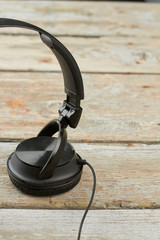 Wall Mural - Headphones on wooden background, cropped image. Black headphones on vintage wooden planks, vertical image. Modern device for listening music.