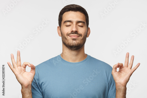 Fotografía Happy smiling man standing with closed eyes, having relaxation while meditating, trying to find balance and harmony isolated