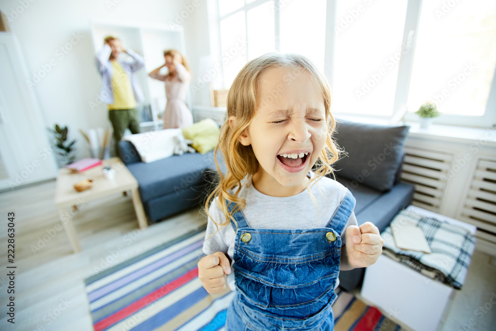 Youthful daughter crying and screaming loudly while being naughty with her shocked parents on background - obrazy, fototapety, plakaty 