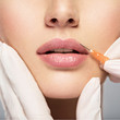 young woman gets botox injection in her lips