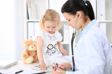 Wall Mural - Doctor and patient baby in hospital. Little girl is being examined by pediatrician with stethoscope. Health care, insurance and help concept