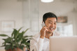 © mavoimages - Smiling Asian businessman talking on a cellphone in an office