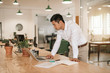 © mavoimages - Asian businessman leaning over his desk working with a laptop