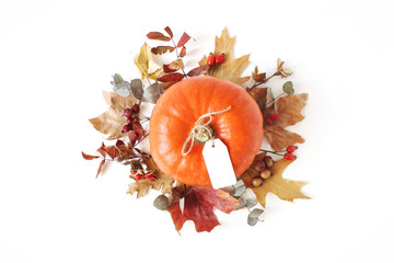 Wall Mural - Autumn floral composition with orange pumpkin. Wreath made of dry maple, eucalyptus leaves and berries on white table background. Fall, Halloween and Thanksgiving design. Flat lay, top view.