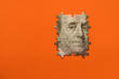 puzzle with Benjamin Franklin's portrait from banknotes on orange background