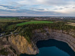 (Luftaufnahme, Drohne) Panorama mit blauem Kratersee im Steinbruch im Vordergrund