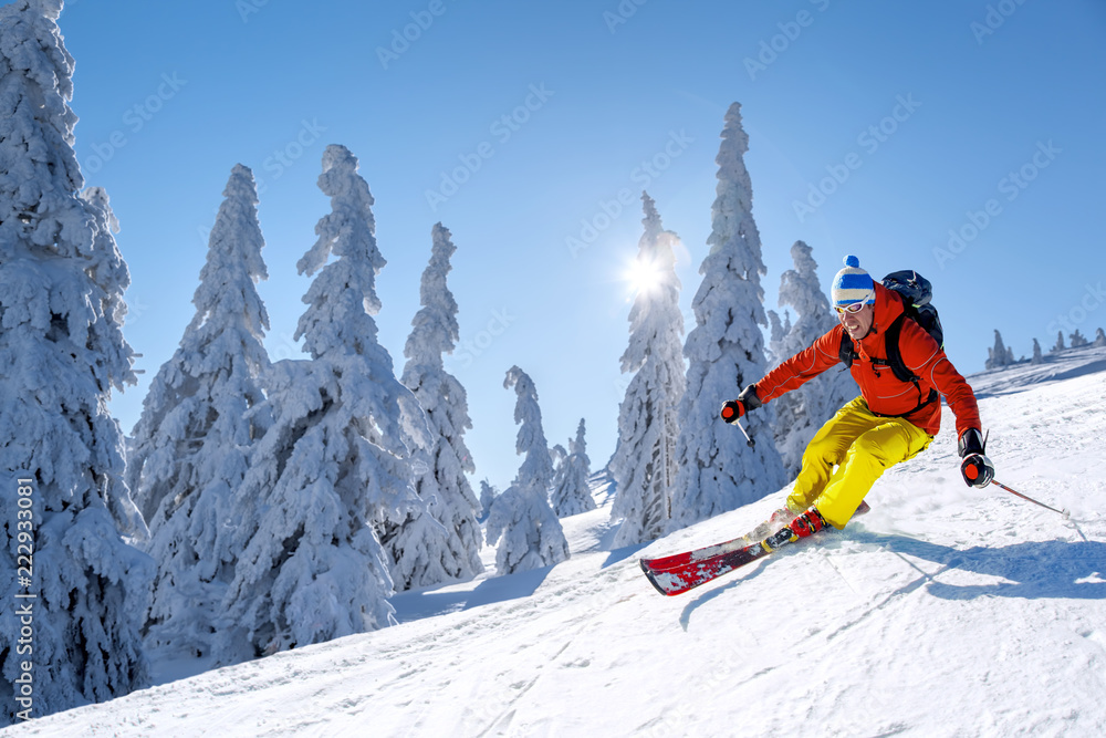 Skier skiing downhill in high mountains against blue sky - obrazy, fototapety, plakaty 