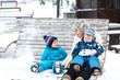 © Irina Schmidt - Young mother with two little toddler boys sitting on bench in winter park. Woman playing and hugging with cute baby sons.